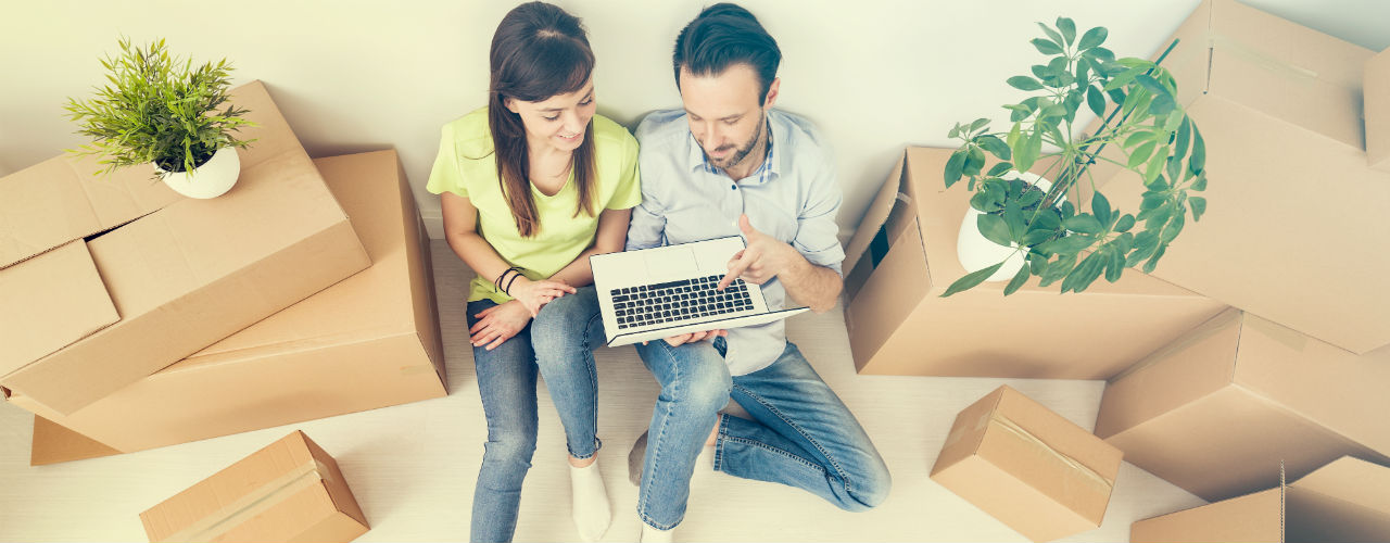 Young couple, just moved in to new property, looking on laptop